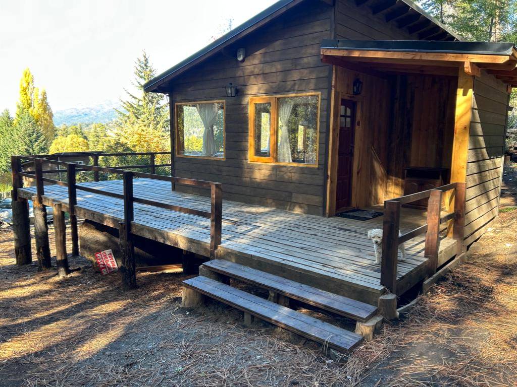 Wooden cabin with deck and steps, among the trees