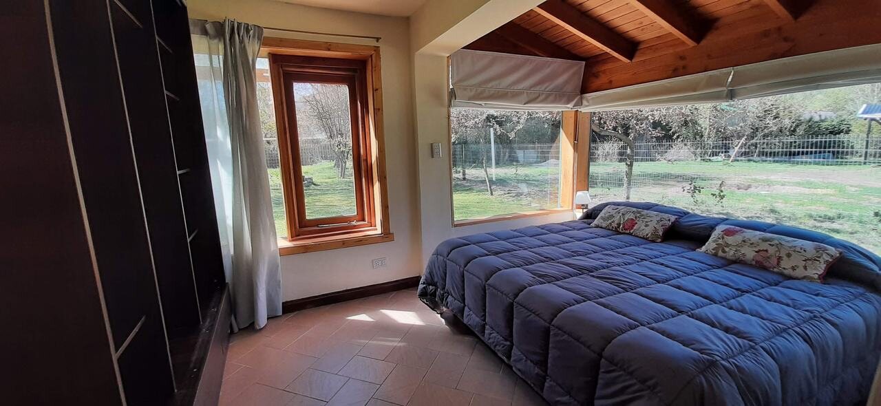 Dormitorio con cama de dos plazas y ventanal al parque