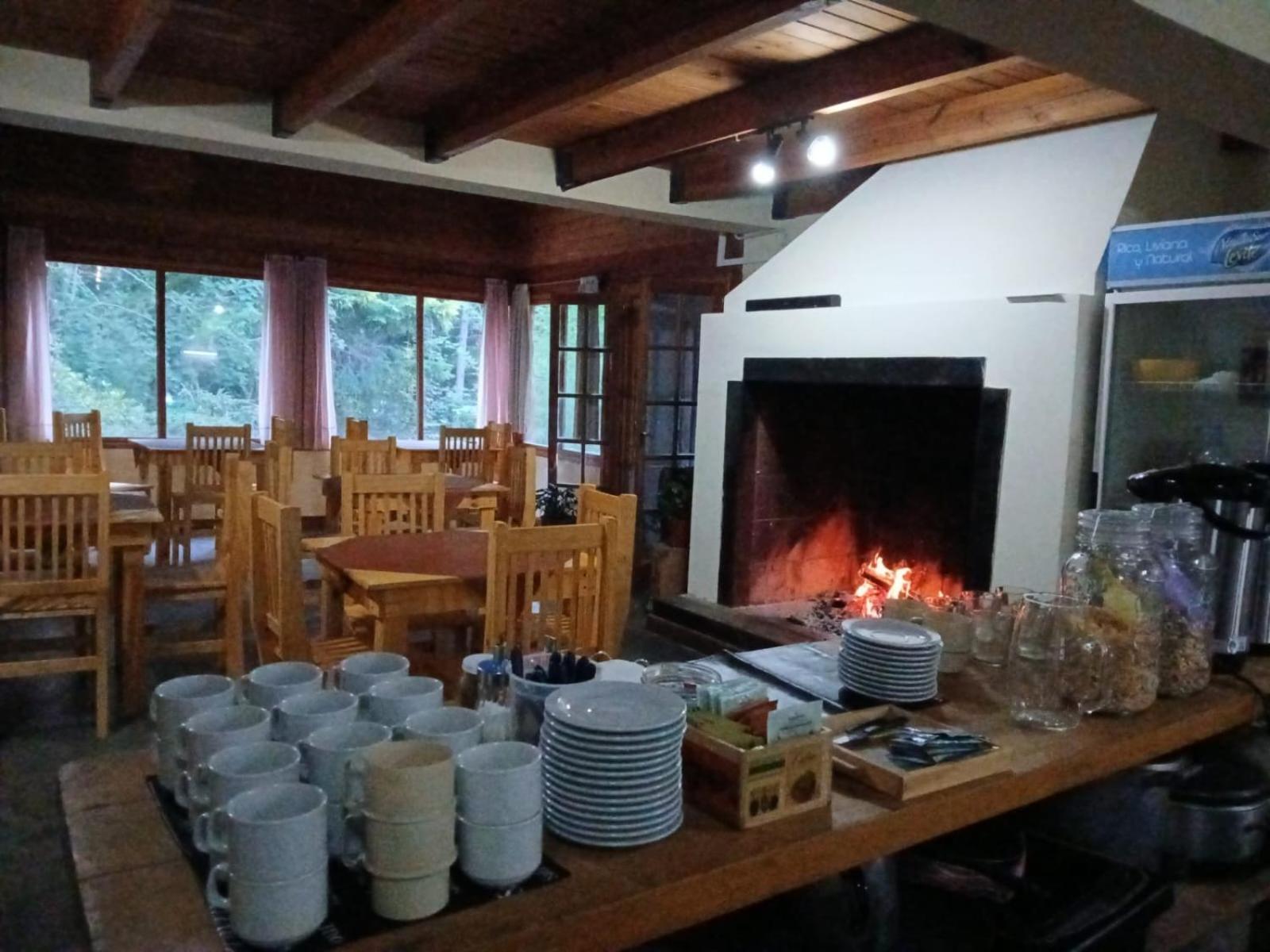 Dining room with a lit wood-burning fireplace and wooden tables
