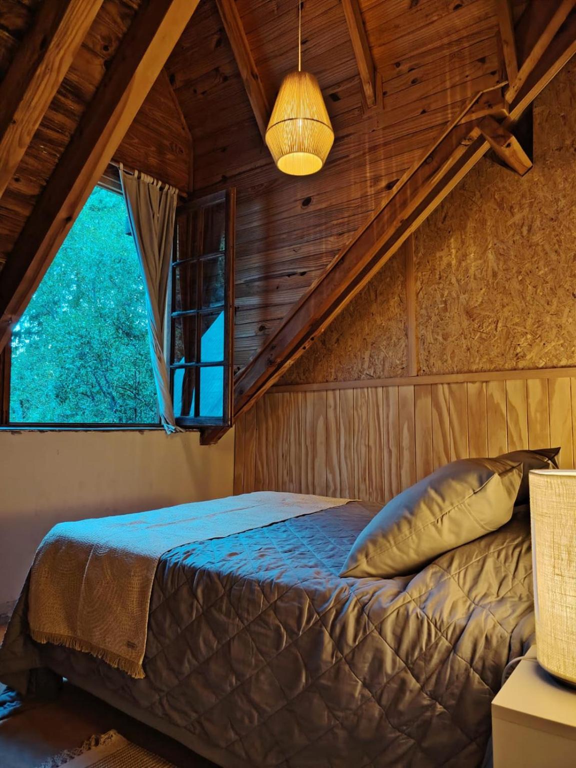 Double bed by a window looking onto the trees