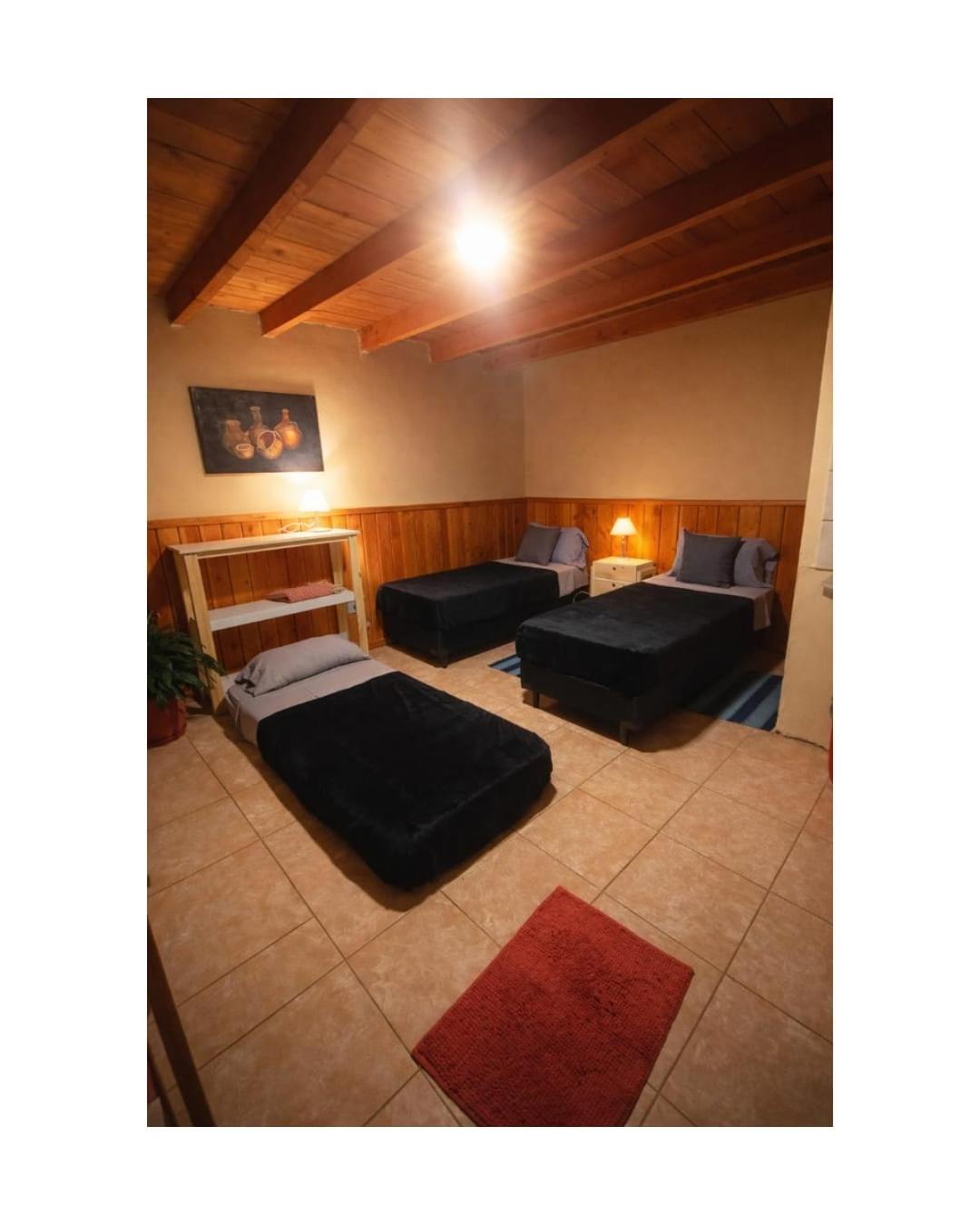 Room with three low beds and a wooden ceiling
