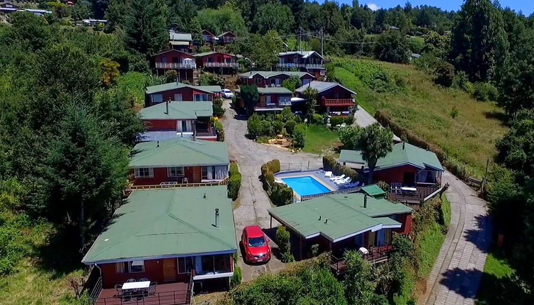 Vista aérea de las cabañas Alto Misimali entre el bosque, con la piscina
