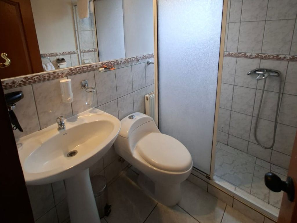 Baño privado con ducha, lavamanos y revestimiento cerámico