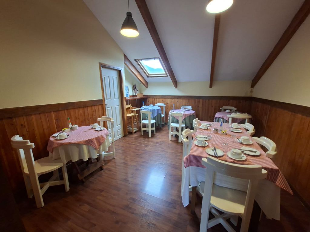 Comedor con mesas servidas, piso de madera y techo con vigas