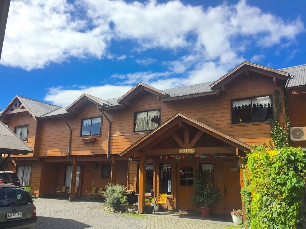 Fachada de madera del Hotel El Montañes bajo un cielo con nubes