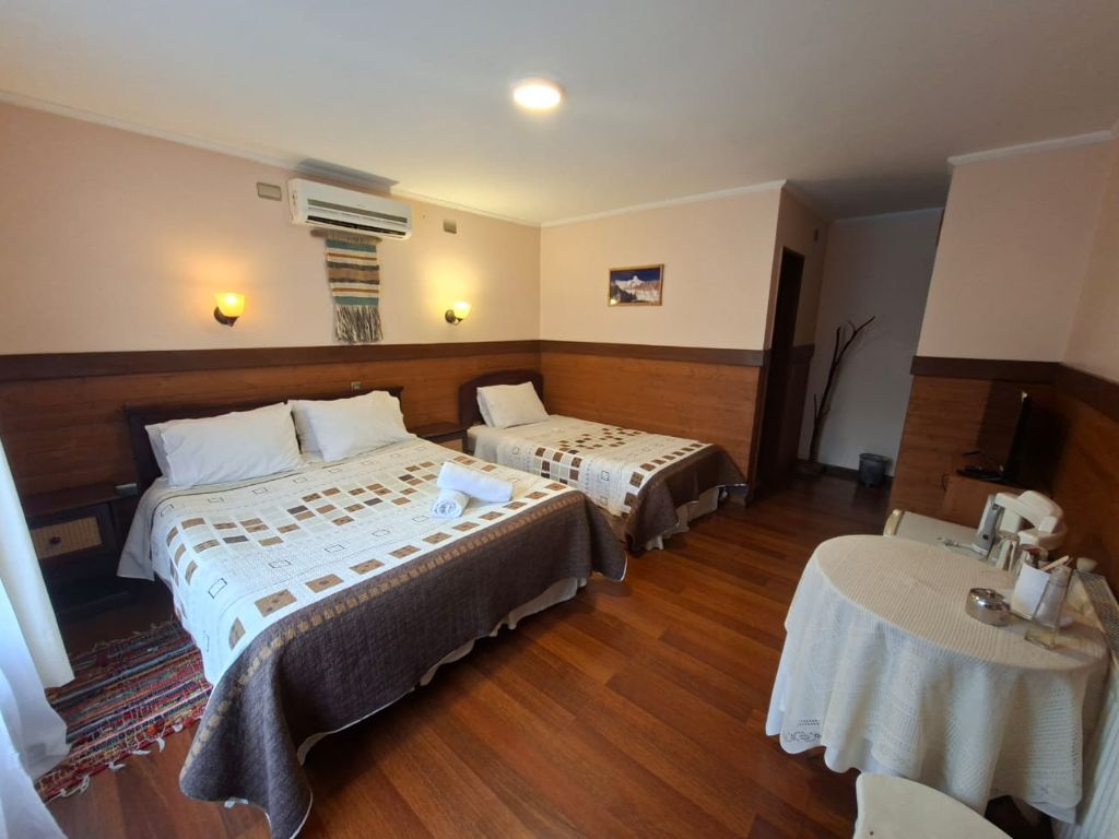 Habitación con cama matrimonial, cama individual y mesa redonda con juego de té