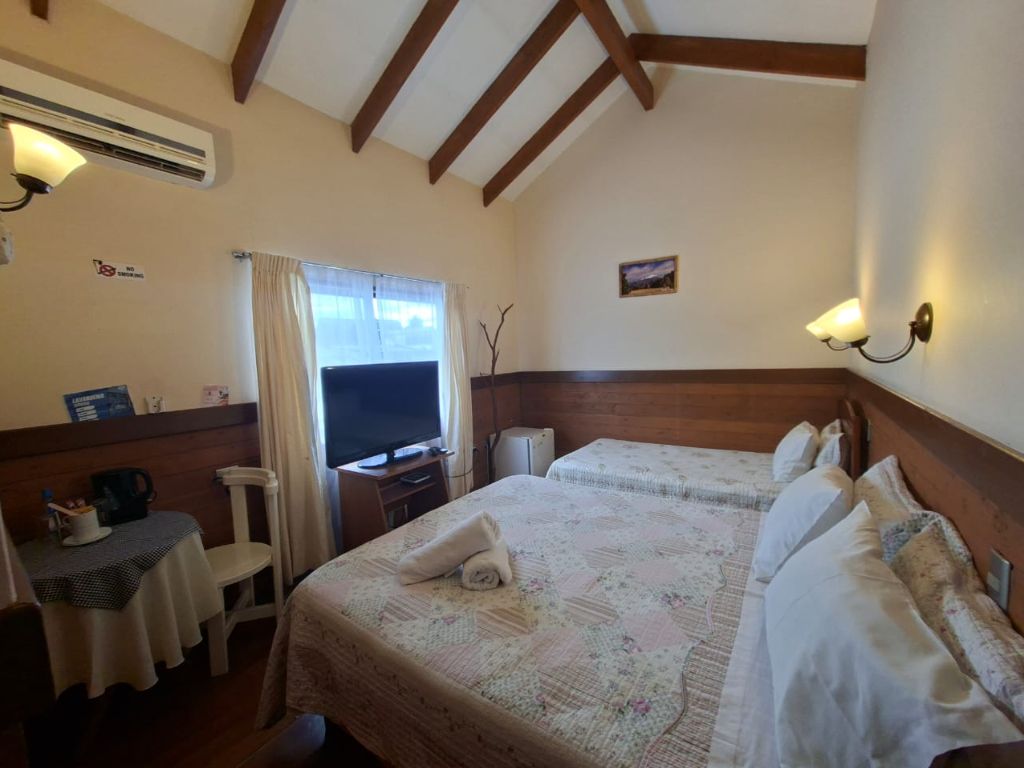 Habitación con techo de vigas de madera, televisor y camas con cubrecamas floreados