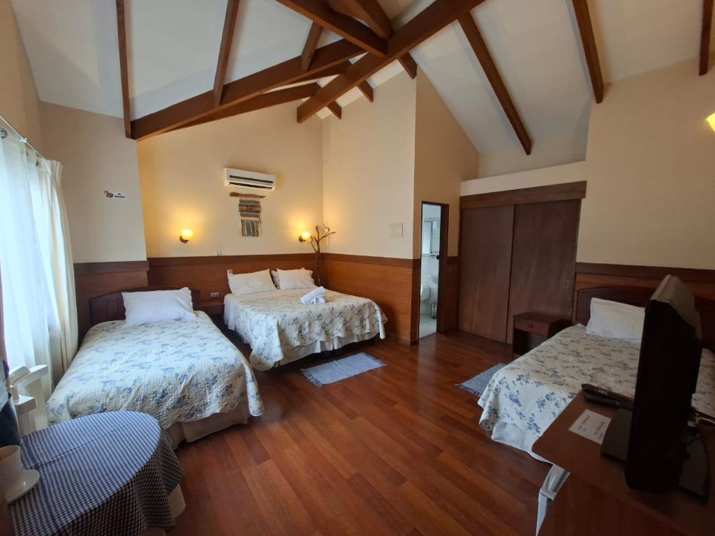 Habitación matrimonial con cabecera de madera, televisor y minibar