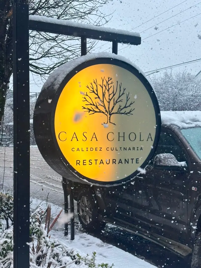 Cartel luminoso de Casa Chola, calidez culinaria, bajo la nieve