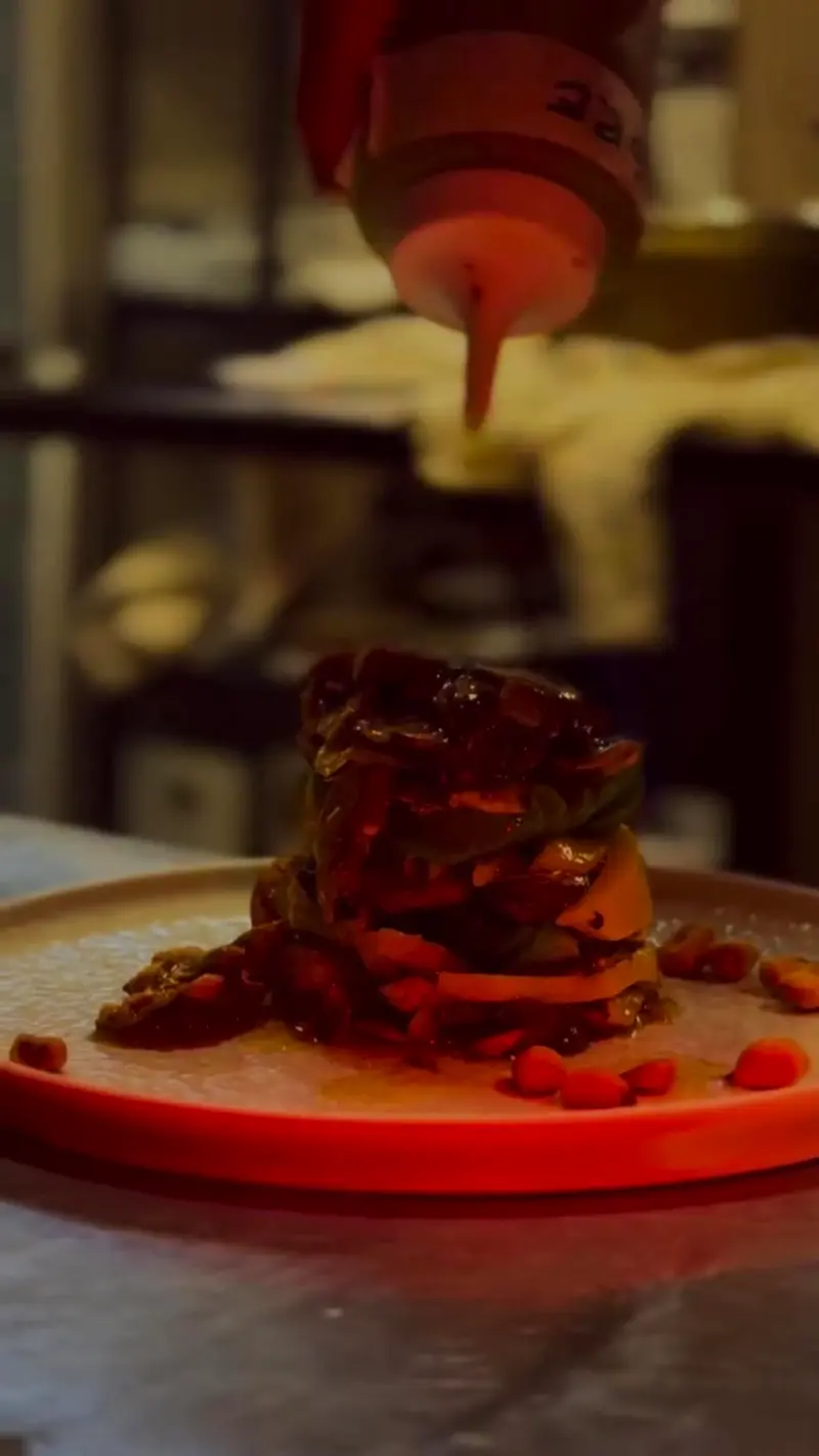 Se termina de salsear un plato de cocina de autor servido en un plato naranja