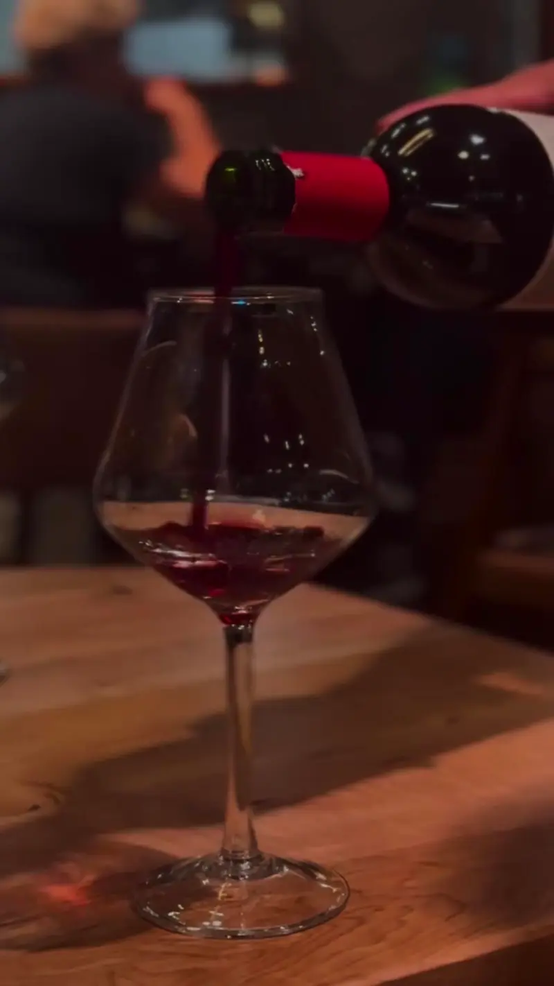 Se sirve vino tinto en una copa sobre una mesa de madera