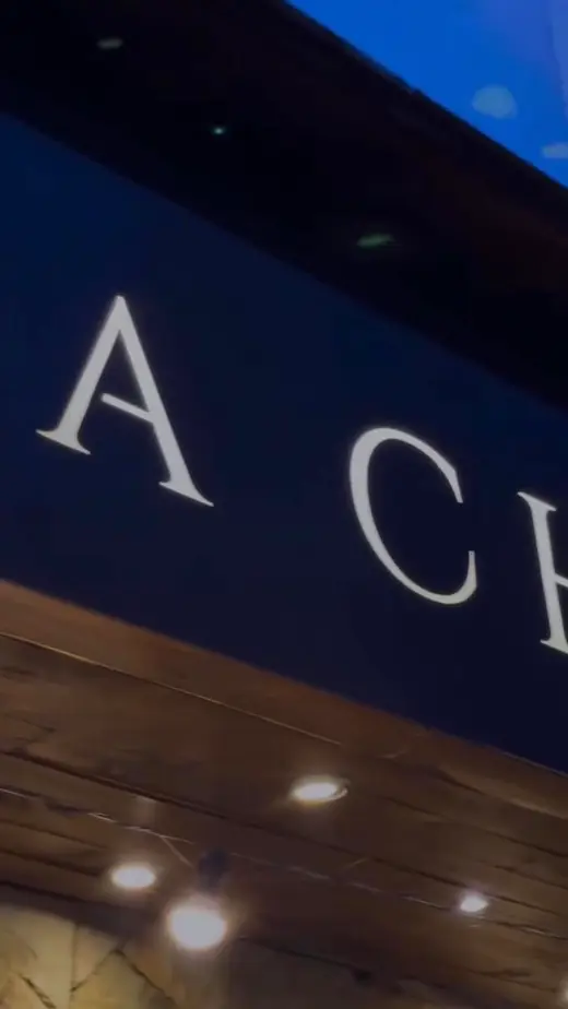Letras del cartel de Casa Chola iluminado de noche, con luces cálidas debajo