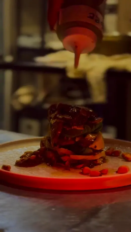 Se termina de salsear un plato de cocina de autor servido en un plato naranja