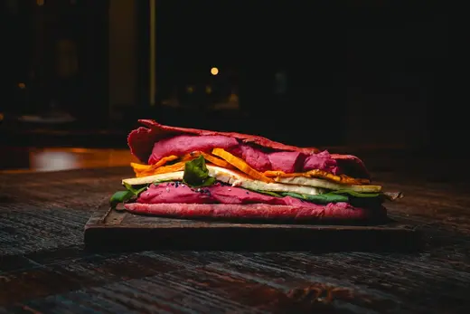 Sándwich veggie con pan de remolacha sobre una tabla de madera
