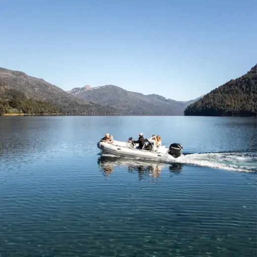 Lancha navegando en un lago de aguas cristalinas rodeado de montañas