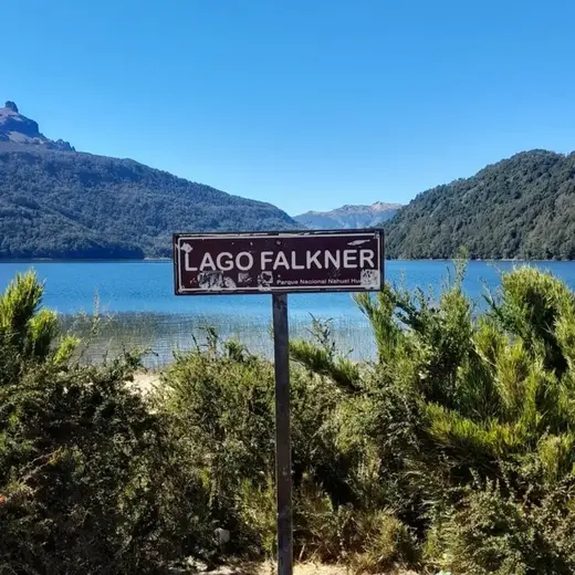 Cartel del Lago Falkner junto a la ruta, con el lago y las montañas al fondo