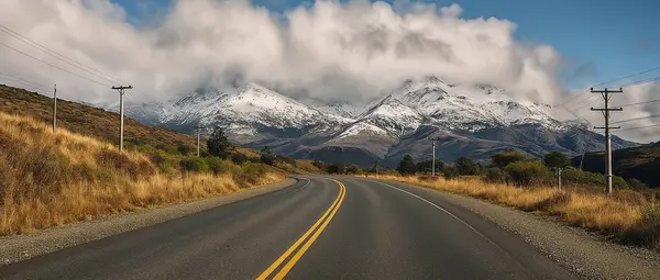 Ruta patagónica con la cordillera nevada y nubes al fondo