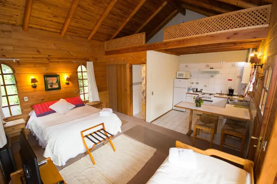 Interior de una cabaña con altillo, cama y cocina