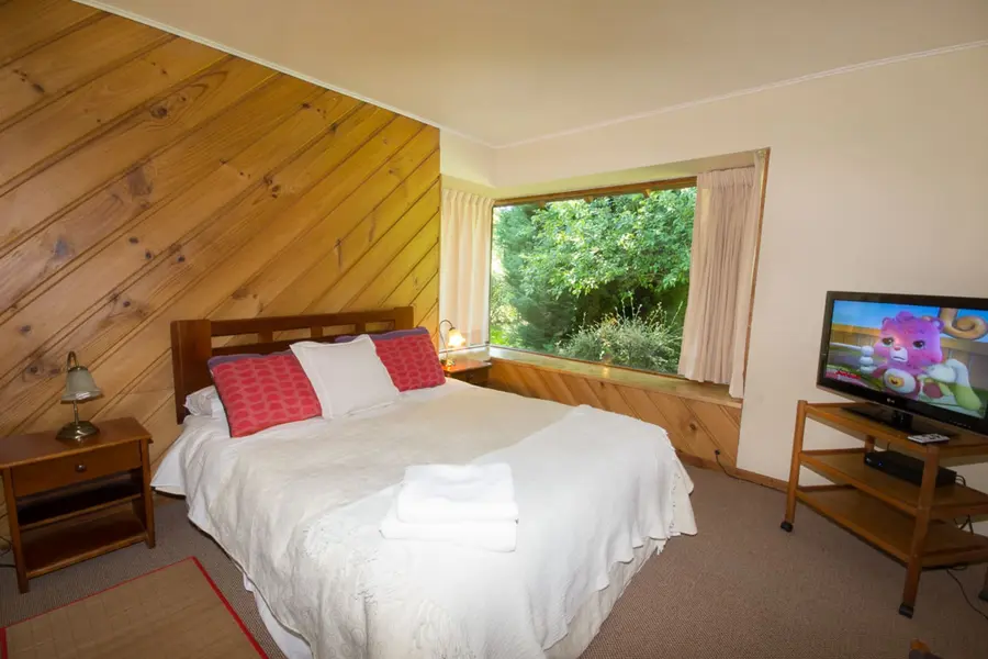 Dormitorio con cama matrimonial y una ventana al jardín