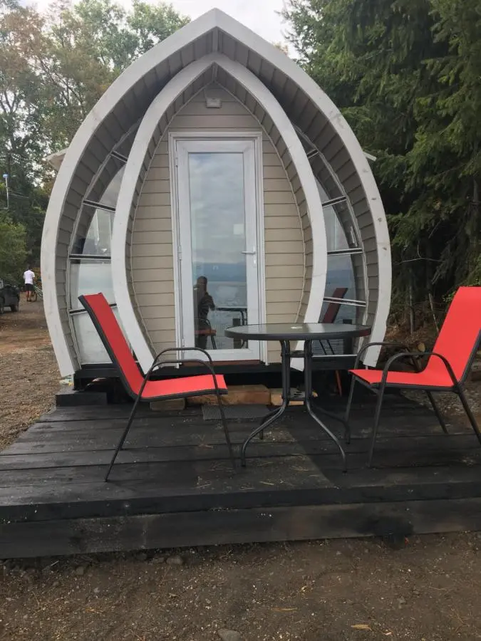 Terraza de la tiny house con mesa y sillas rojas y el lago de fondo