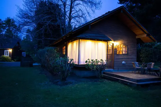Cabaña de madera con luces cálidas al anochecer