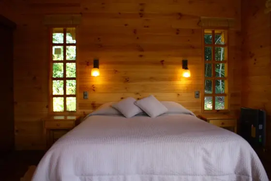 Dormitorio con cama matrimonial y paredes de madera