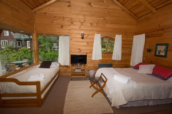 Interior con camas, televisor y ventanales al jardín