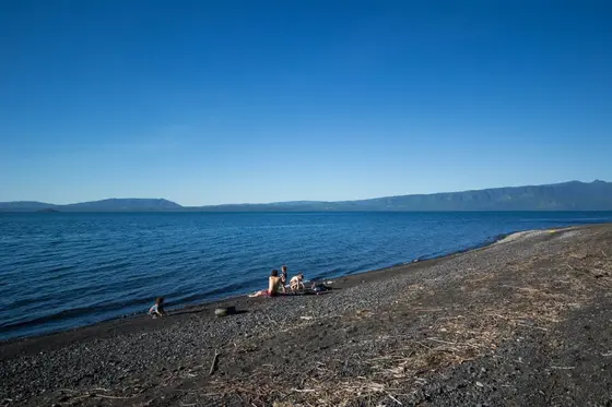 Playa de piedras junto al lago Villarrica bajo un cielo despejado