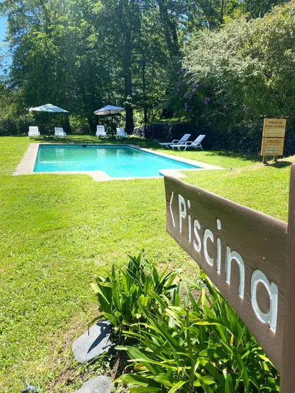 Piscina rodeada de césped con un cartel de madera que dice Piscina
