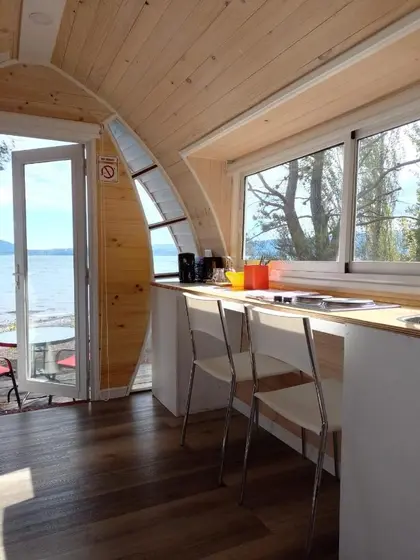 Interior de madera clara de la tiny house con ventanales