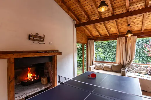 Sala con hogar a leña y ventanal al jardín