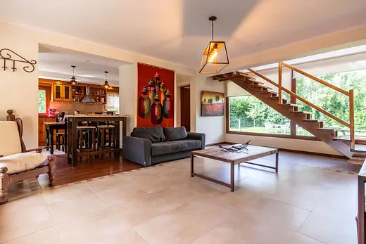 Living-comedor con escalera de madera y ventanales al jardín