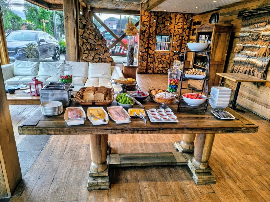 Mesa del desayuno buffet con panes, fiambres, quesos y frutas
