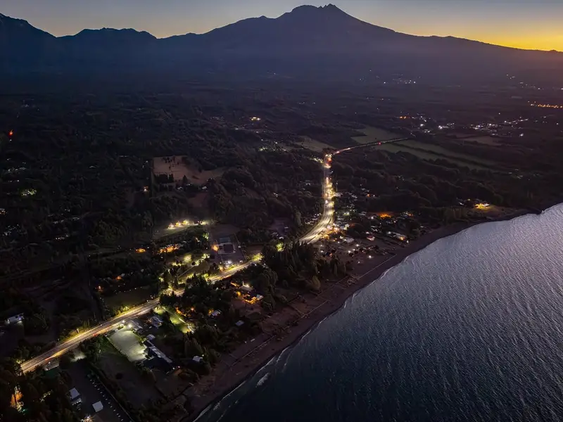 Vista aérea de la costa de Ensenada al anochecer, con el volcán Calbuco