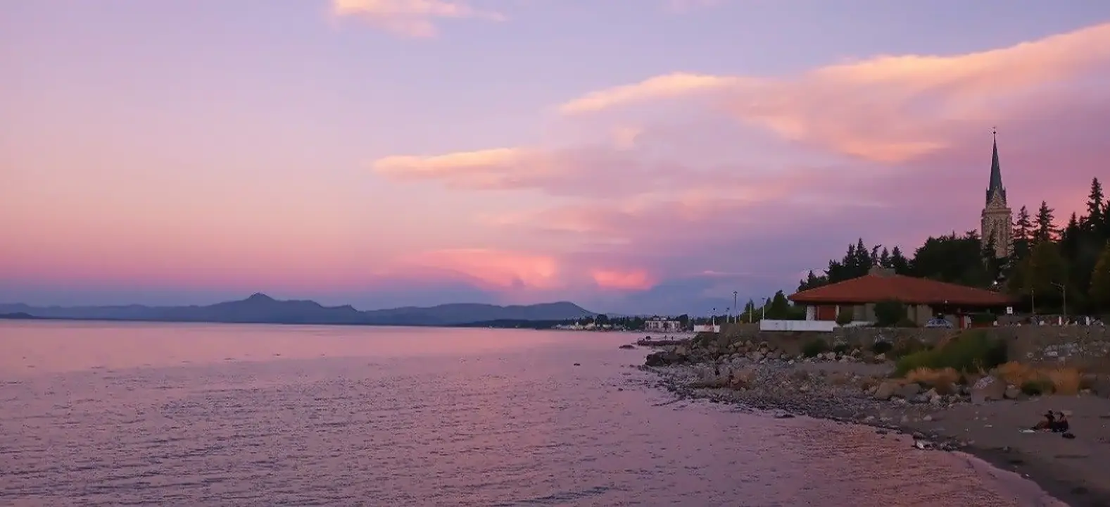 Atardecer rosado sobre la costa del lago, con la catedral de Bariloche