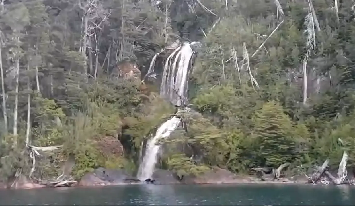 Una cascada en dos saltos entre el bosque, a orillas del lago