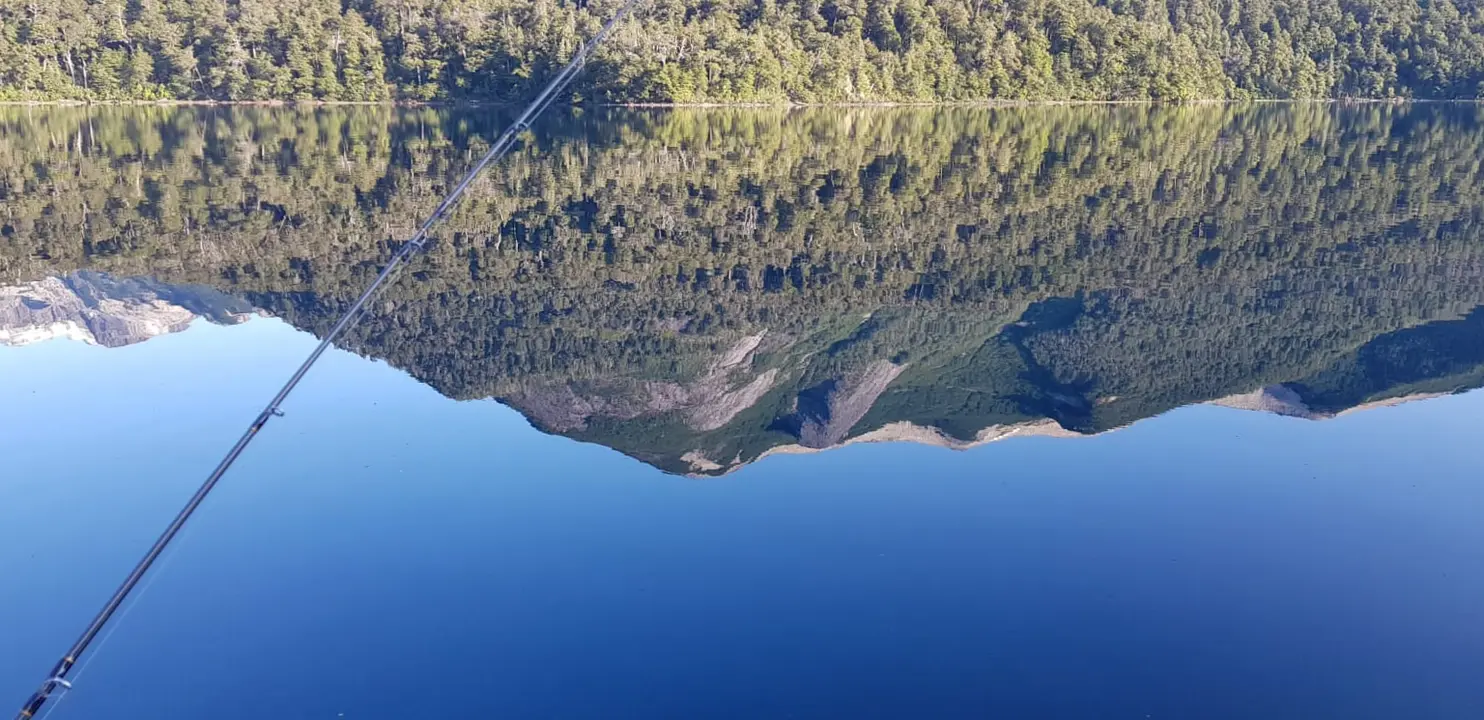 El cerro reflejado en el lago quieto, con la caña lista