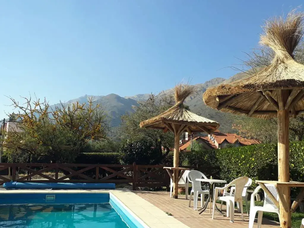 La piscina con sombrillas de paja y las sierras de fondo
