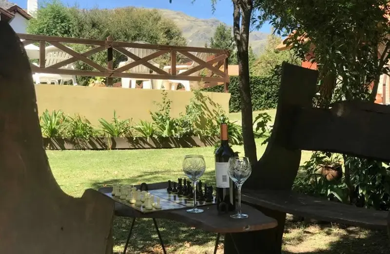 Bancos de madera con un tablero de ajedrez y una botella de vino en el parque