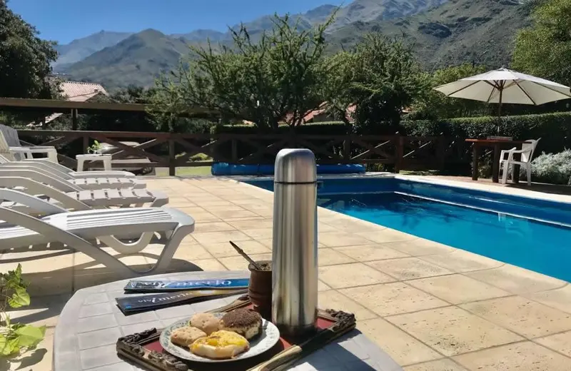 Un termo, mate y facturas junto a la piscina, con la sierra de fondo