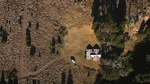 Vista aérea de una casa rodeada de campo y árboles