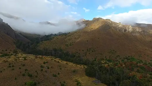 Vista aérea de cerros con nubes bajas y bosque en otoño