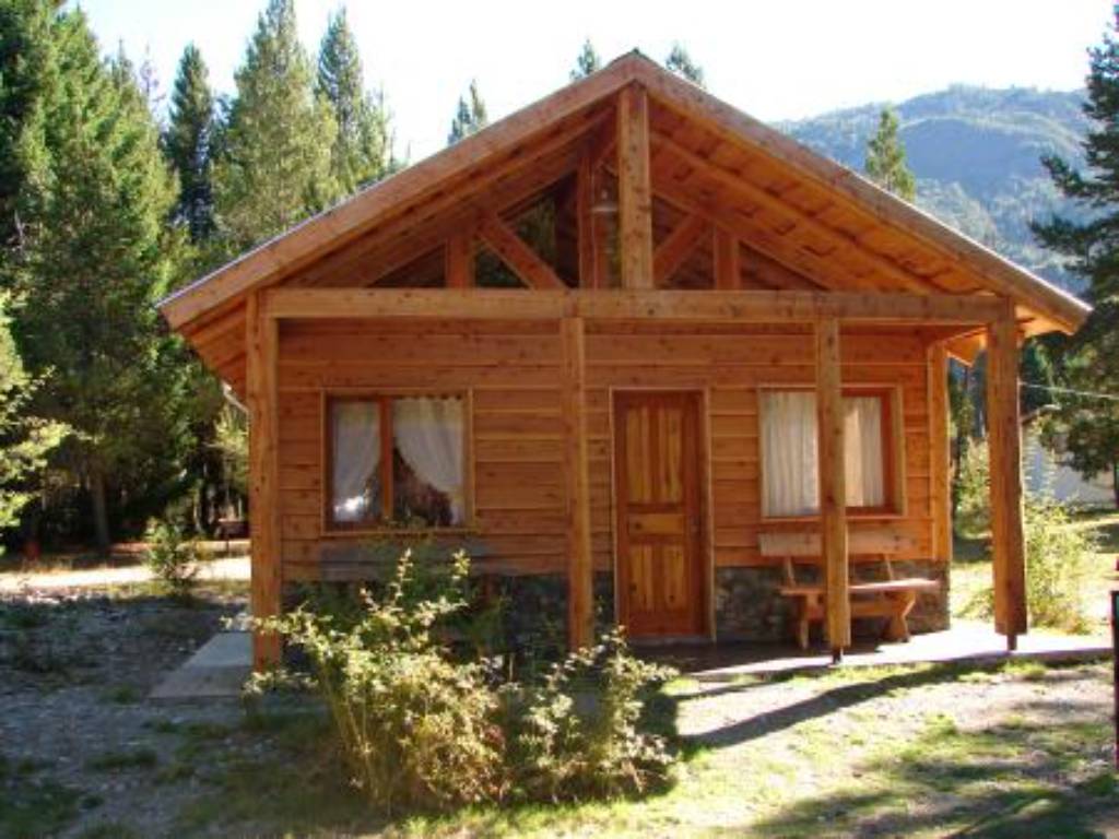 Cabaña de madera con galería y cerros de fondo