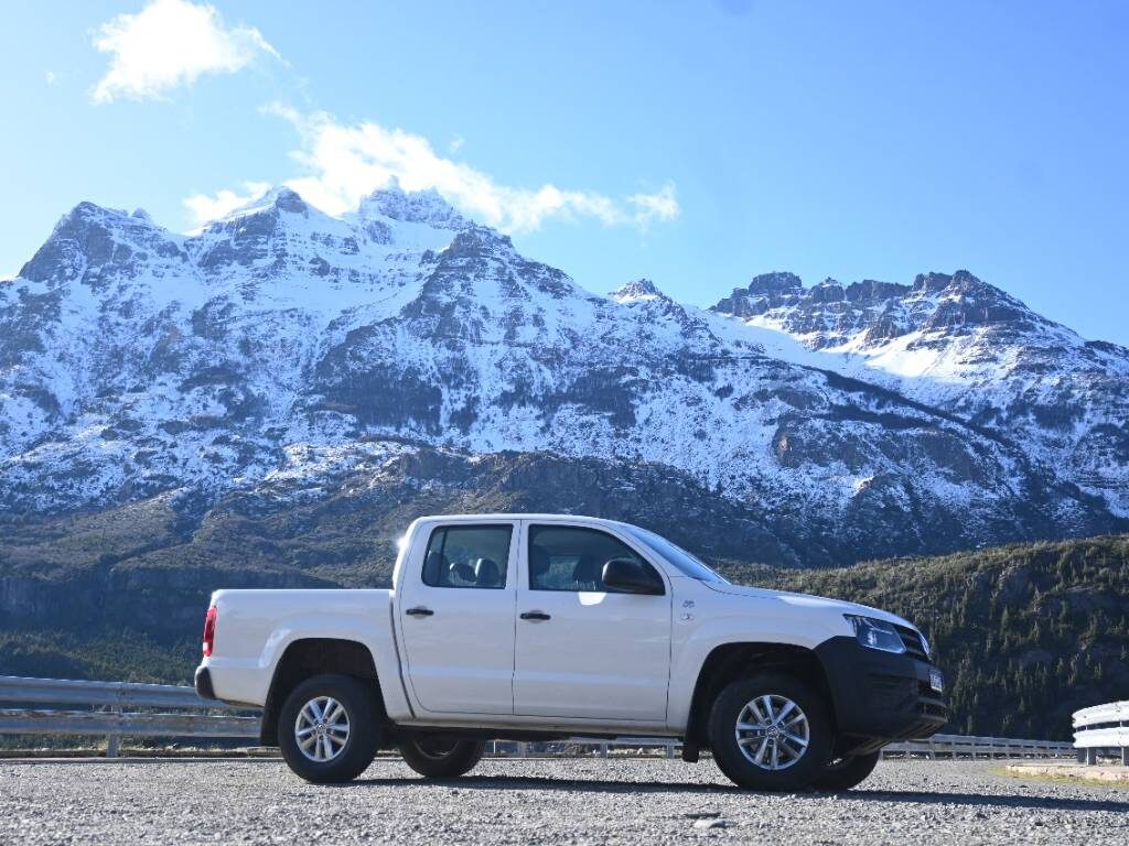 Amarok de la flota en un camino de montaña frente a la cordillera nevada