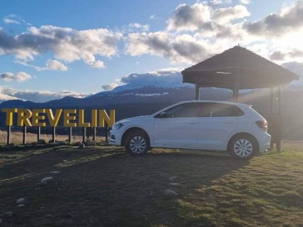 Volkswagen Polo de la flota junto al cartel de Trevelin